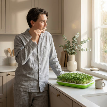 Man standing in a kitchen with a tray of sprouts on a counter