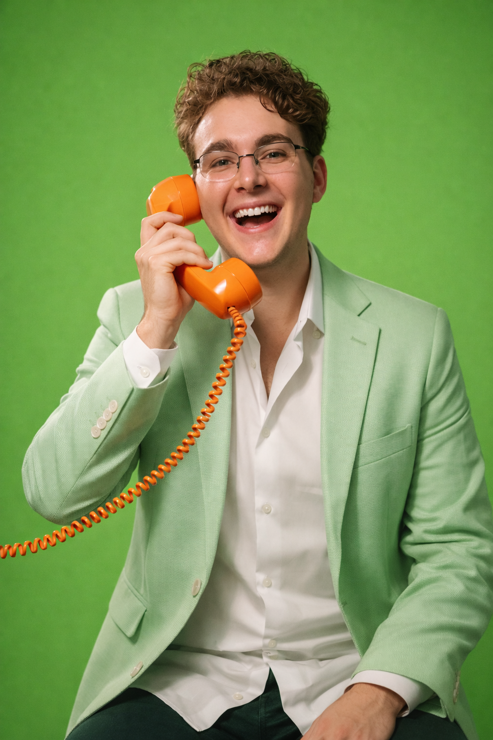 Connor Hiebel in a light green blazer holding an orange phone against a green background