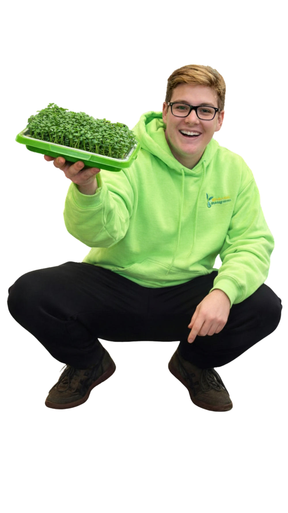 Connor Hiebel in a bright green hoodie holding a tray of broccoli microgreen plants on a white background